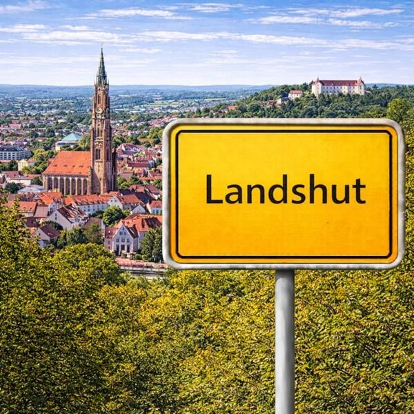 Gelbes Ortsschild Landshut mit Stadt im Hintergrund