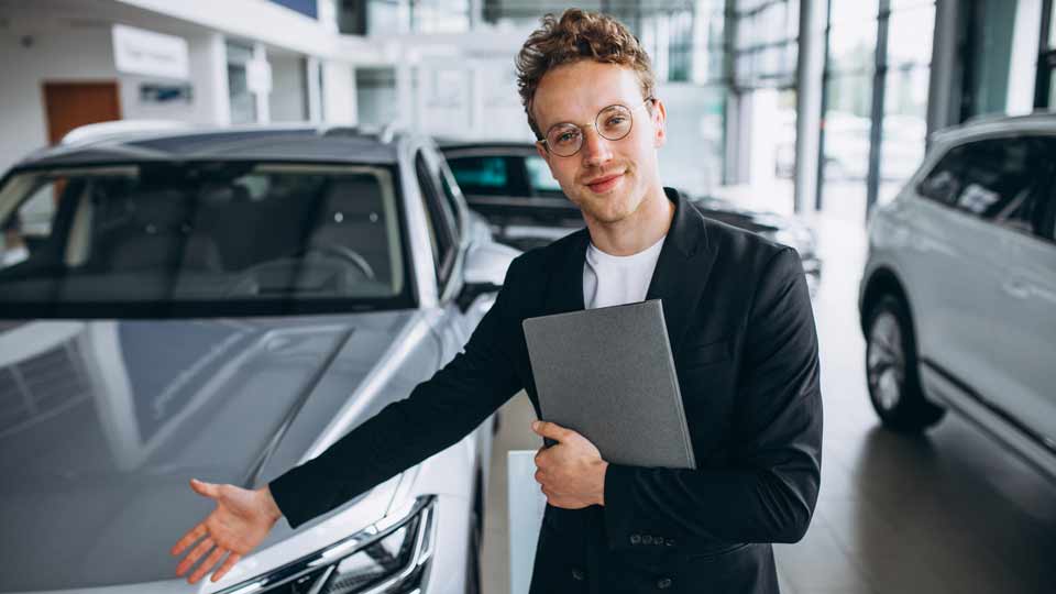 Ein Verkäufer zeigt auf ein Auto und erklärt dem Kunden die Konditionen beim Auto verkaufen Landshut